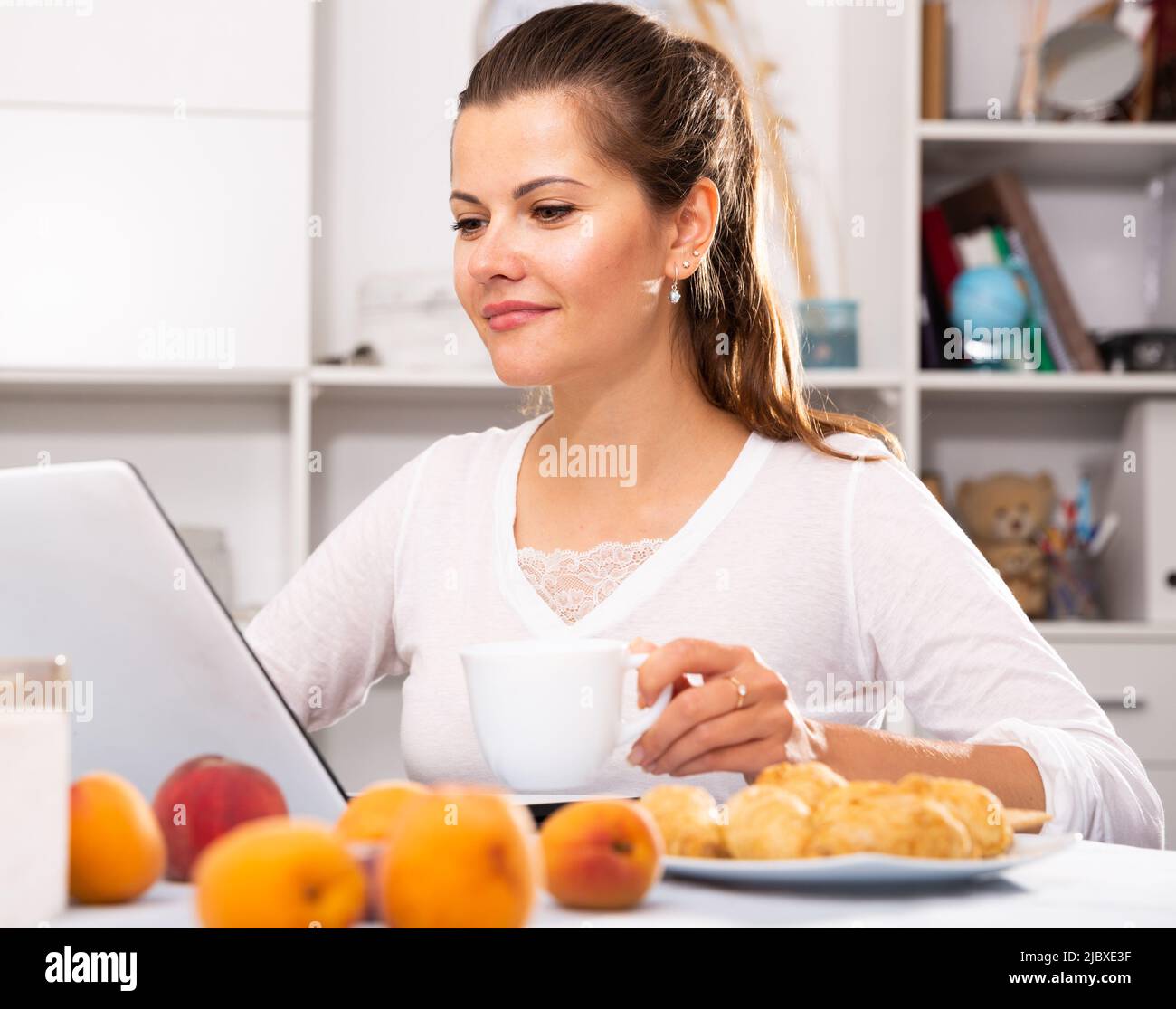 Woman with laptop during breakfast Stock Photo