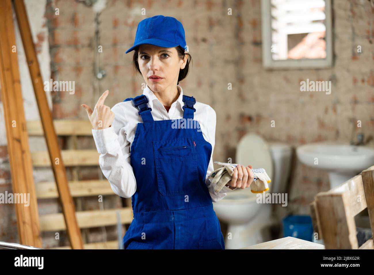 Portrait of confident female foreman in blue overalls in building under construction Stock Photo