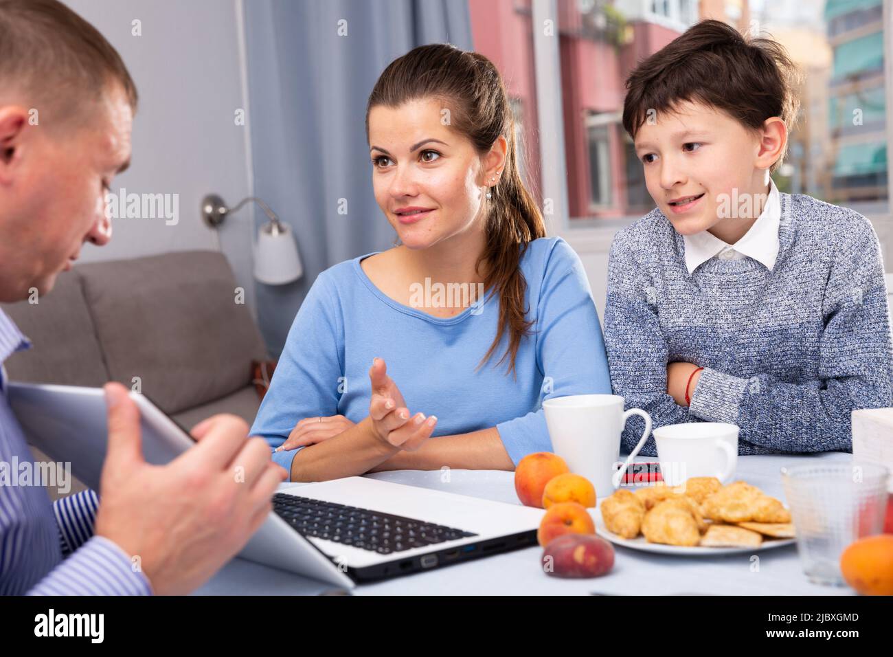 Happy family communicating over breakfast at home in morning Stock Photo