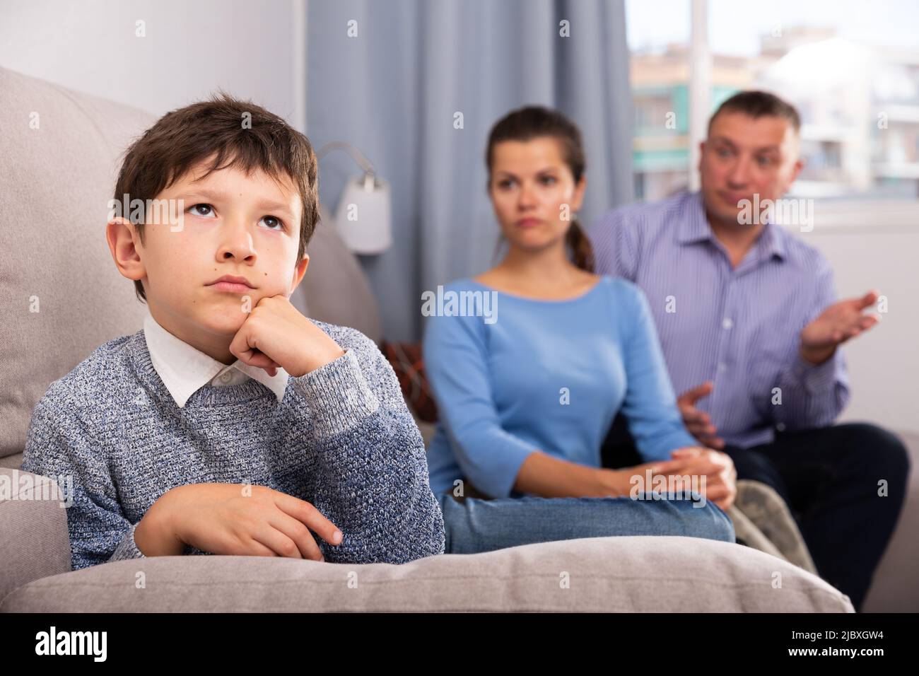 Portrait of offended boy after quarrel with parents sitting on sofa at home Stock Photo