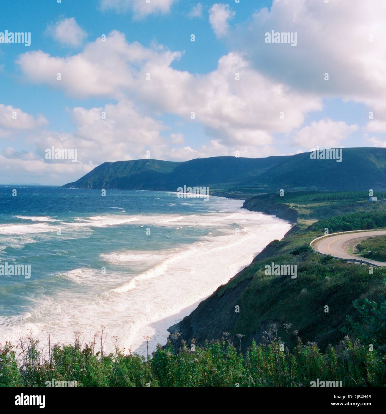 Road along shore with waves and mountains behind, Cape Breton Island, 2021 Stock Photo