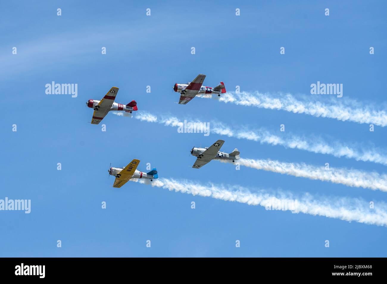 Reading, Pennsylvania, USA-June 6, 2022: Four WWII airplanes trailing smoke do a flyby against a blue sky background during the Mid-Atlantic Museum WW Stock Photo