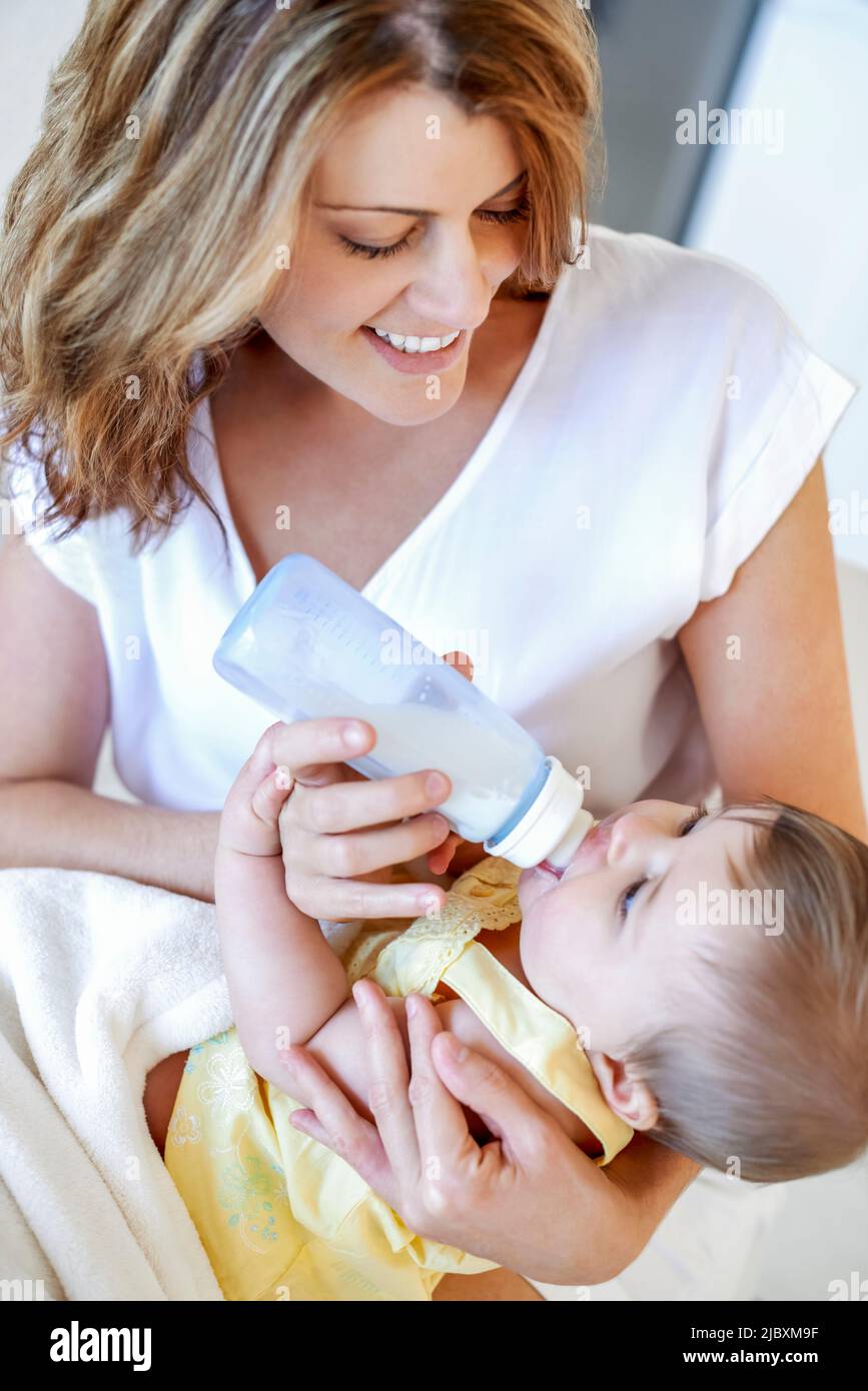Young mother feeding baby daughter a bottle of milk Stock Photo