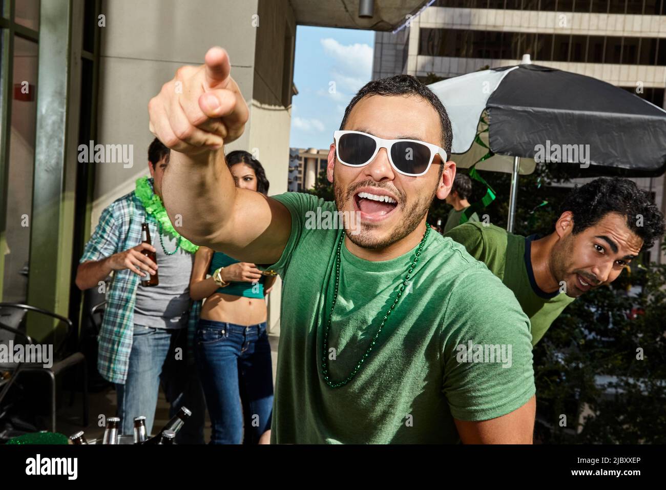 Man smiling and pointing at cameras while at St Patrick's day party. Stock Photo
