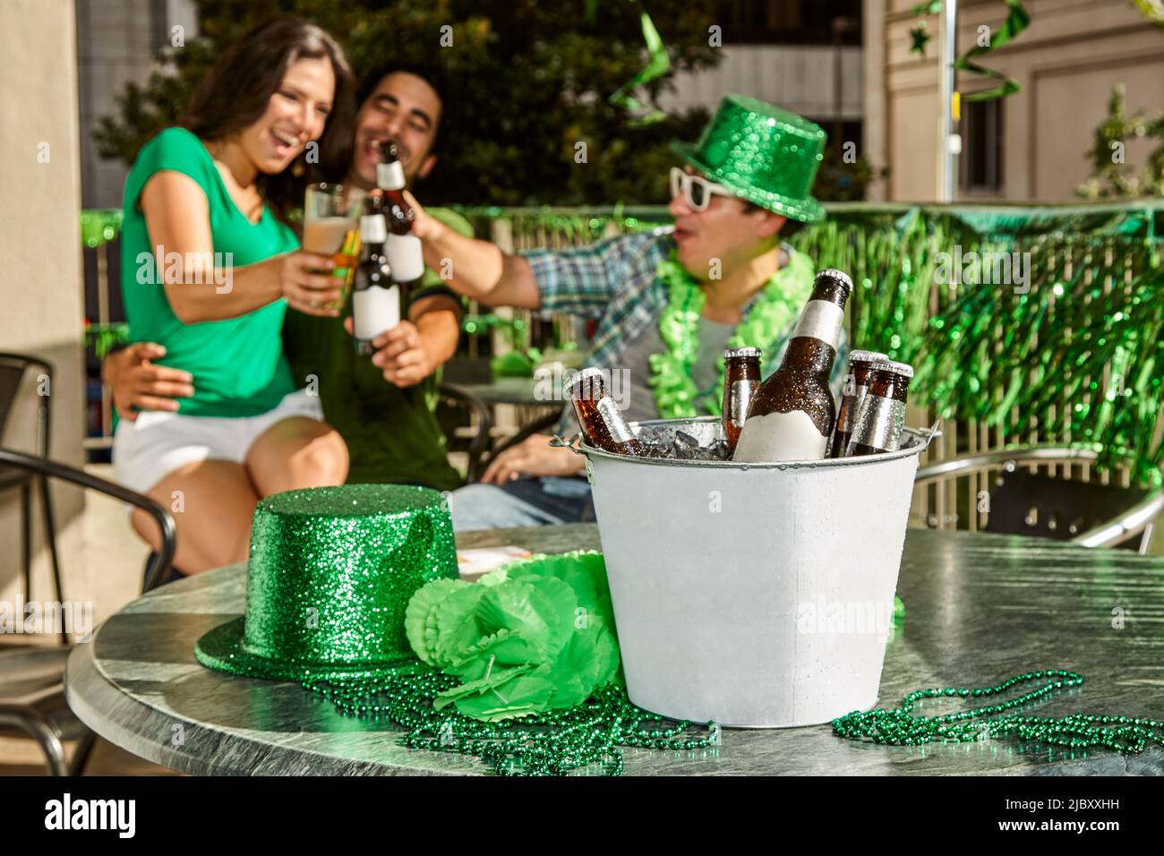 Group of friends toasting in background with a bucket of beer in foreground. Focus on foreground. Stock Photo