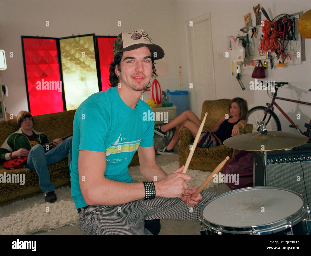 portrait of young garage band drummer practicing with friends in