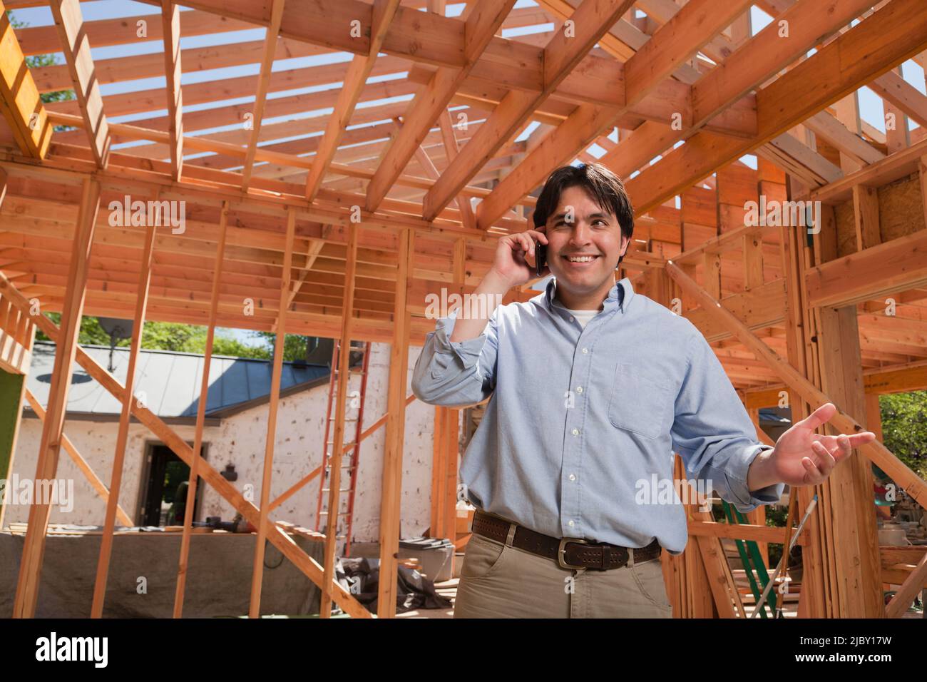 Man talking on his cellular phone at a residential construction site Stock Photo