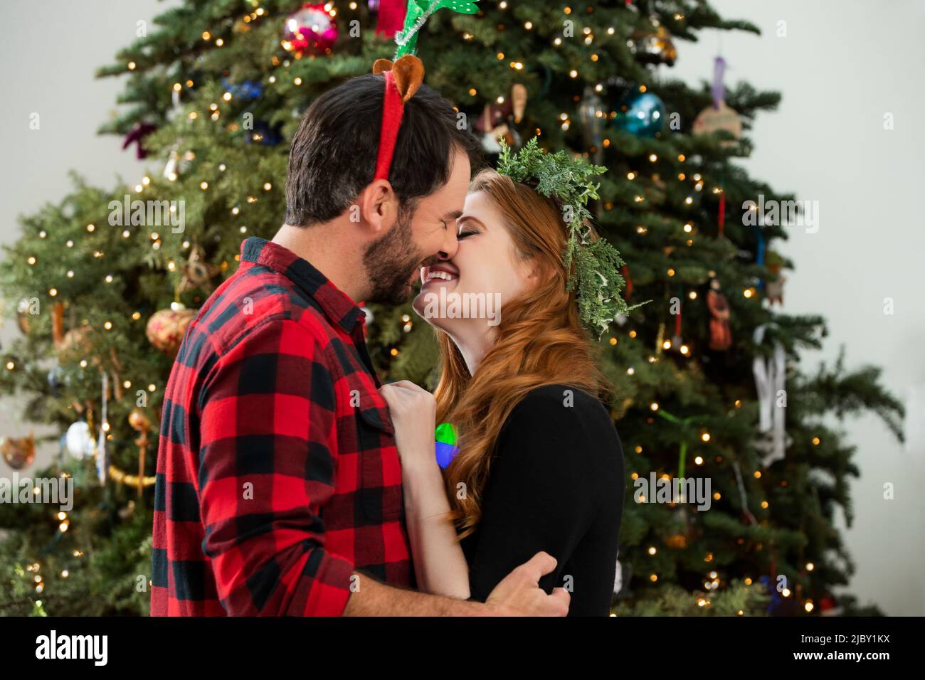 Passionate young couple kissing in front of Christmas tree Stock Photo ...