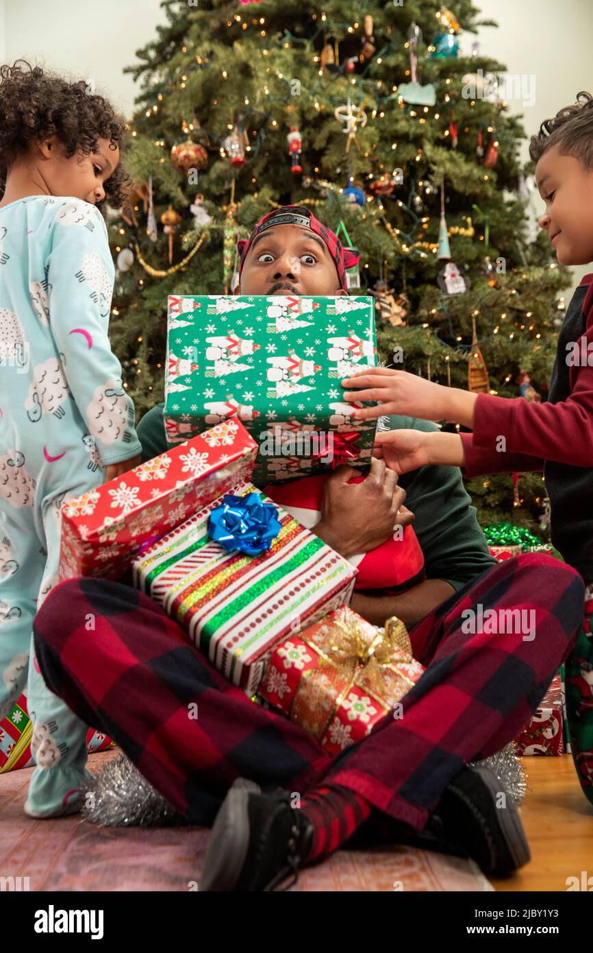 Family playing by Christmas tree. Stock Photo