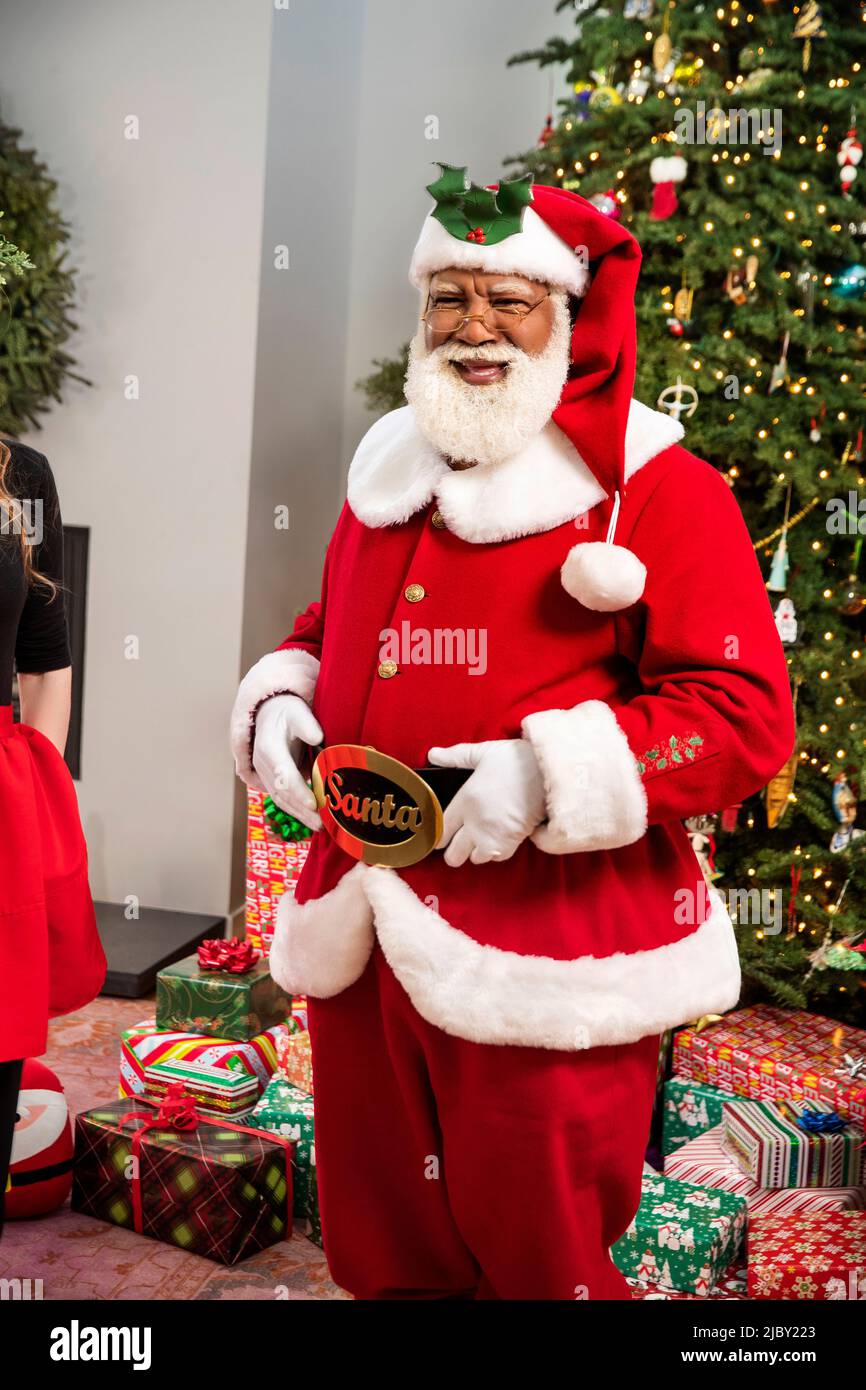 Jolly portrait of Black Santa standing by Christmas tree Stock Photo