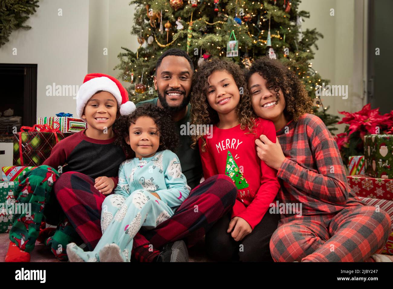 Loving family sitting under Christmas tree posing Stock Photo - Alamy