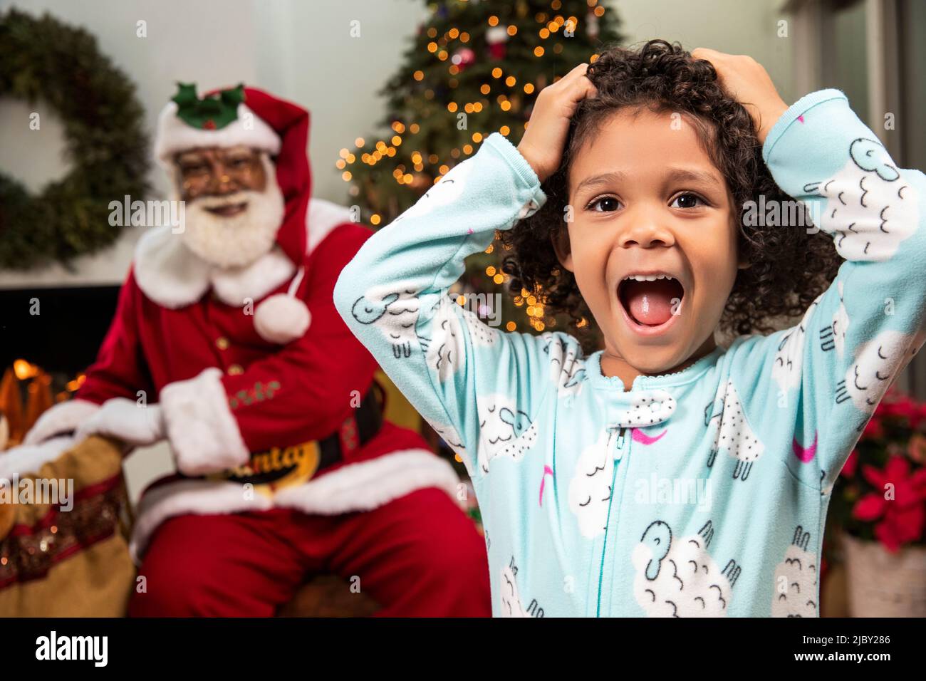 Cute girl in pajamas screaming in surprise as she catches Santa Claus delivering gifts. Black Santa Stock Photo Alamy