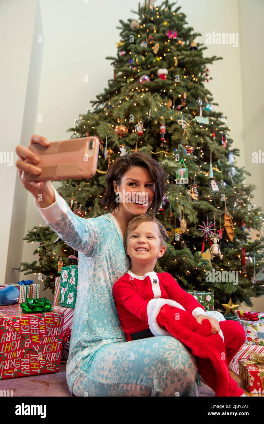 Mother and son taking a selfie in front of Christmas tree Stock Photo