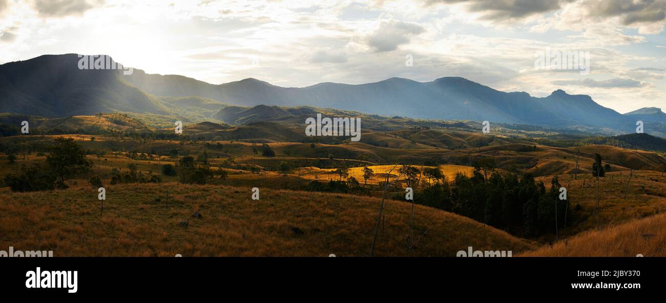 Panorama of sun shining through clouds onto mountain range and rural landscape in the Cunningham Gap - Queensland Stock Photo