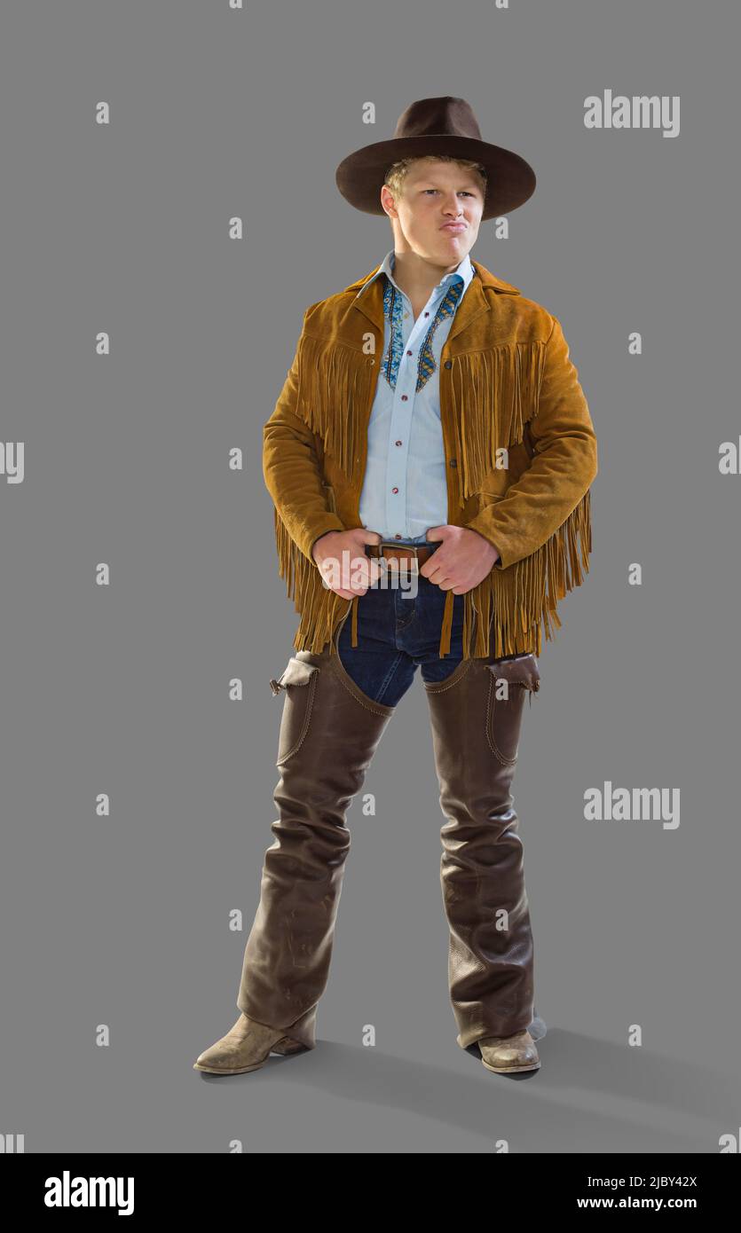 Man in a cowboy costume for Halloween smiling and making at face looking off camera, against a gray background Stock Photo