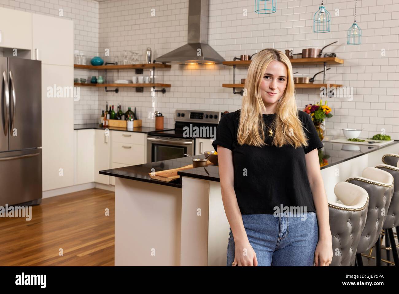 Portrait of a young Caucasian woman standing in kitchen looking at camera confidently. Stock Photo