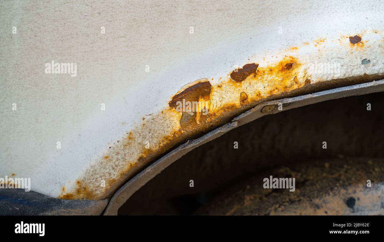 Rust Pocket Car Problem Rust pockets on the wing of a white car close-up. The effect of ...