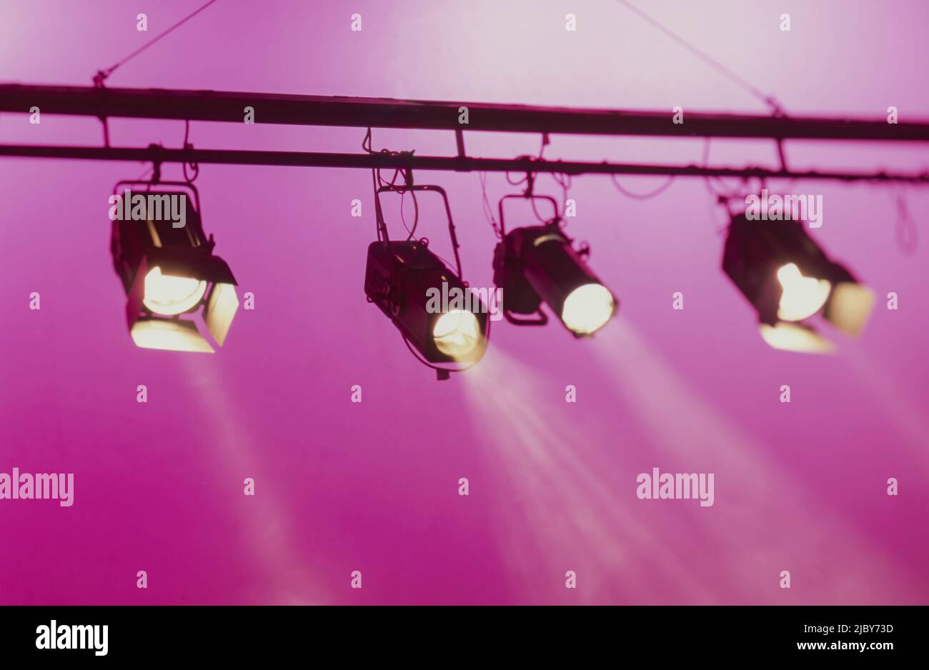 Spotlights shining downwards against pink background Stock Photo