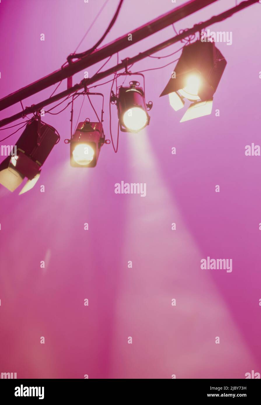 Spotlights shining downwards against pink background Stock Photo