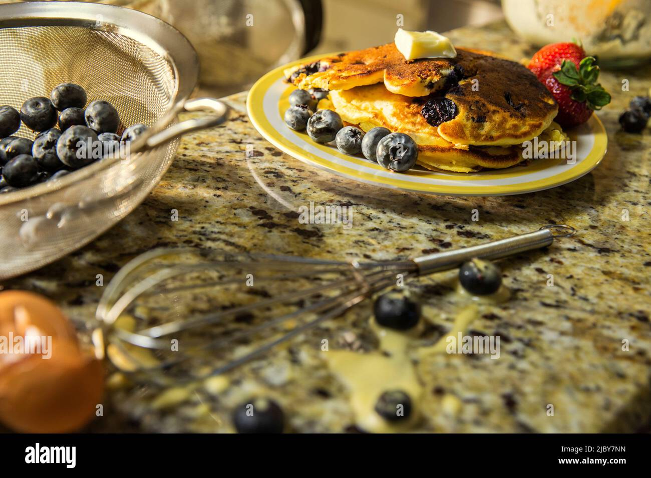 Detail of plate of pancakes with fruit on messy kitchen counter after making blueberry pancakes Stock Photo