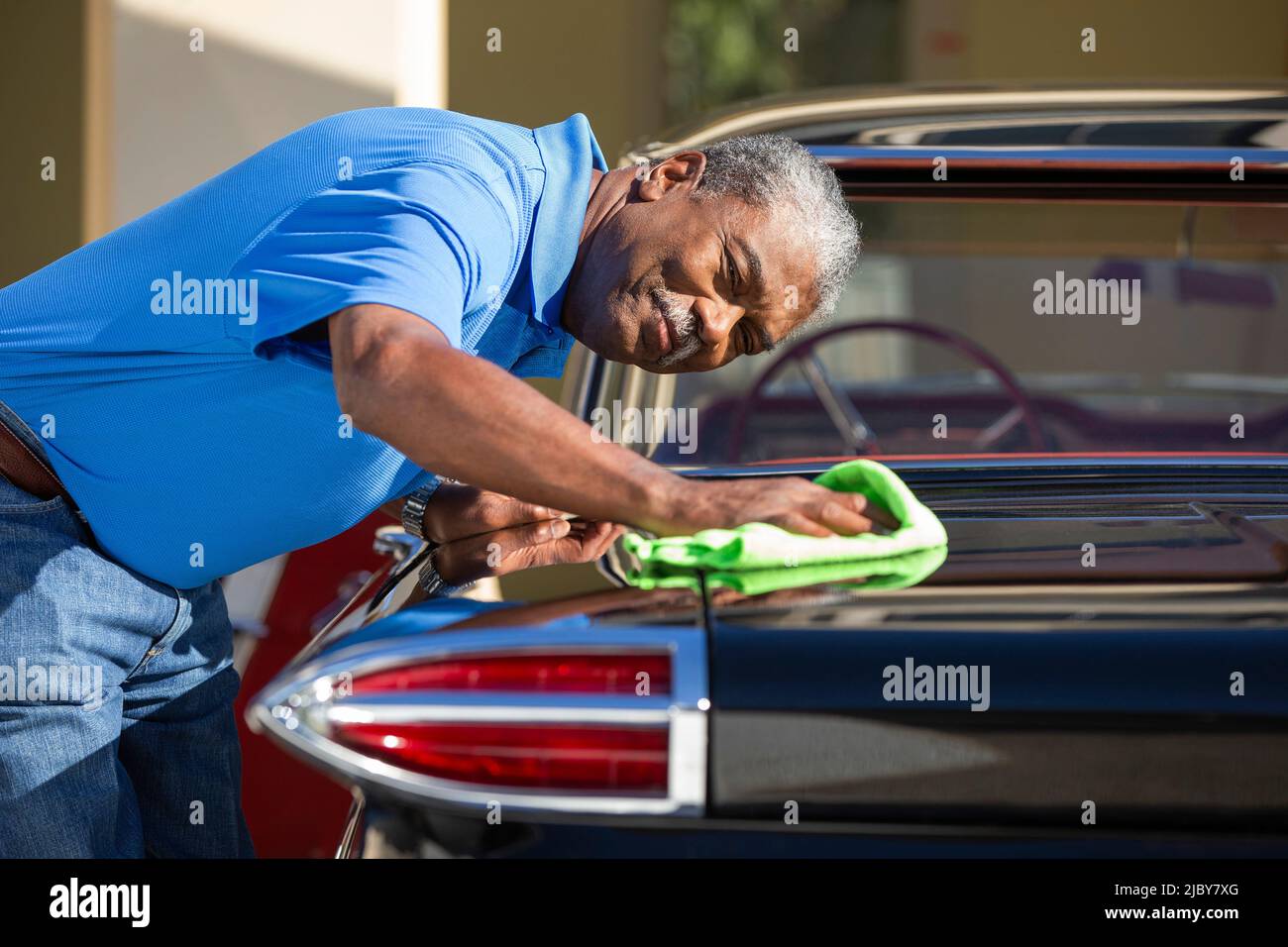 Older man drying off 1960 Oldsmobile Super 88 Holiday Sport Sedan after detailing Stock Photo