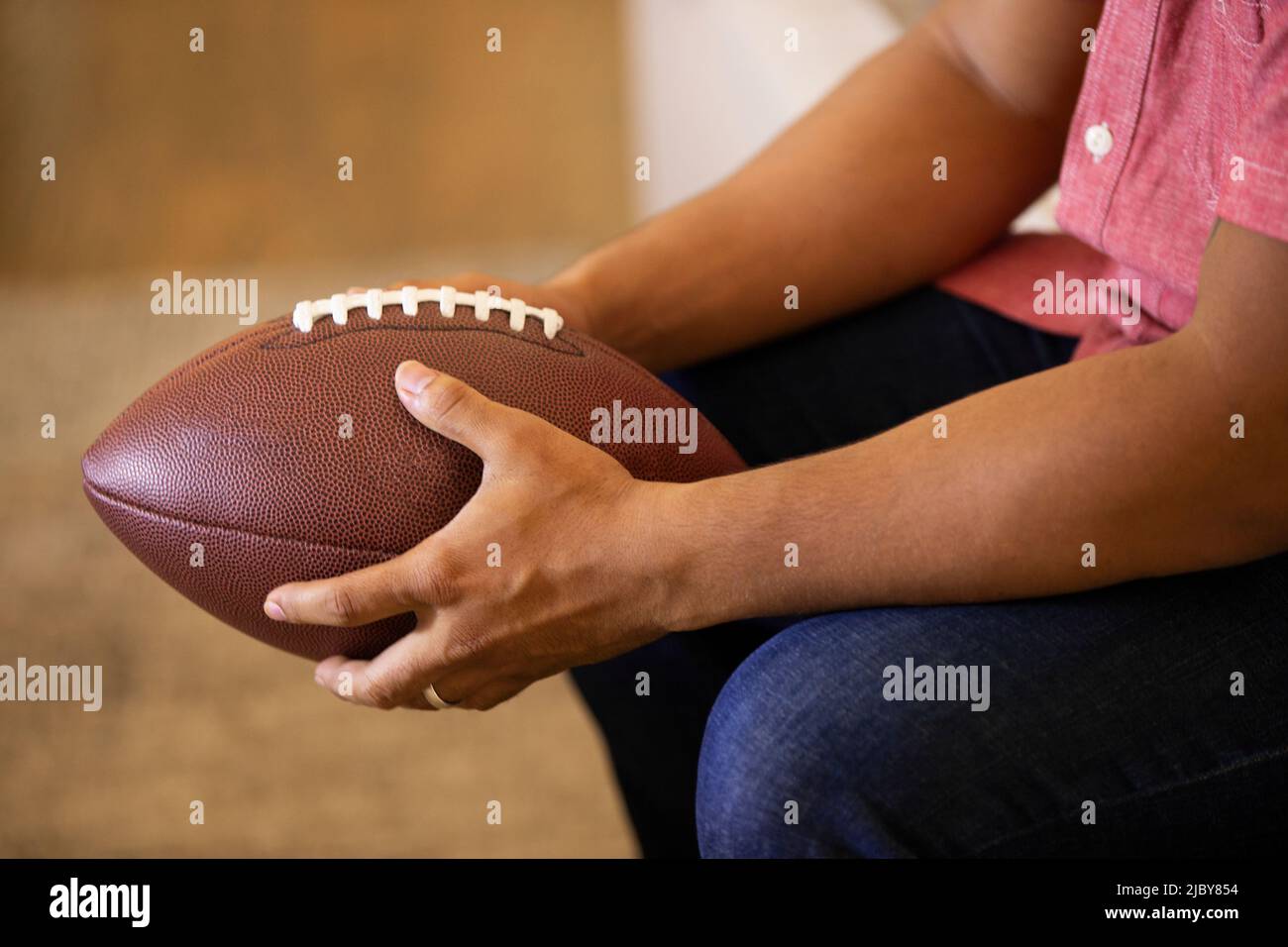 Detail of man holding football while watching game at home Stock Photo