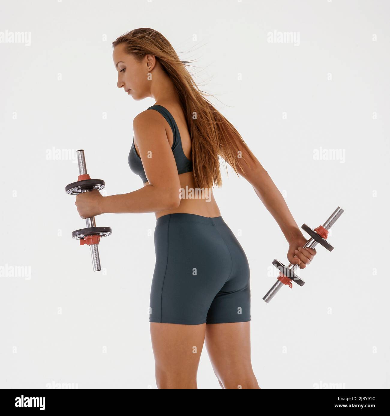 Young woman exercising with dumb bells Stock Photo