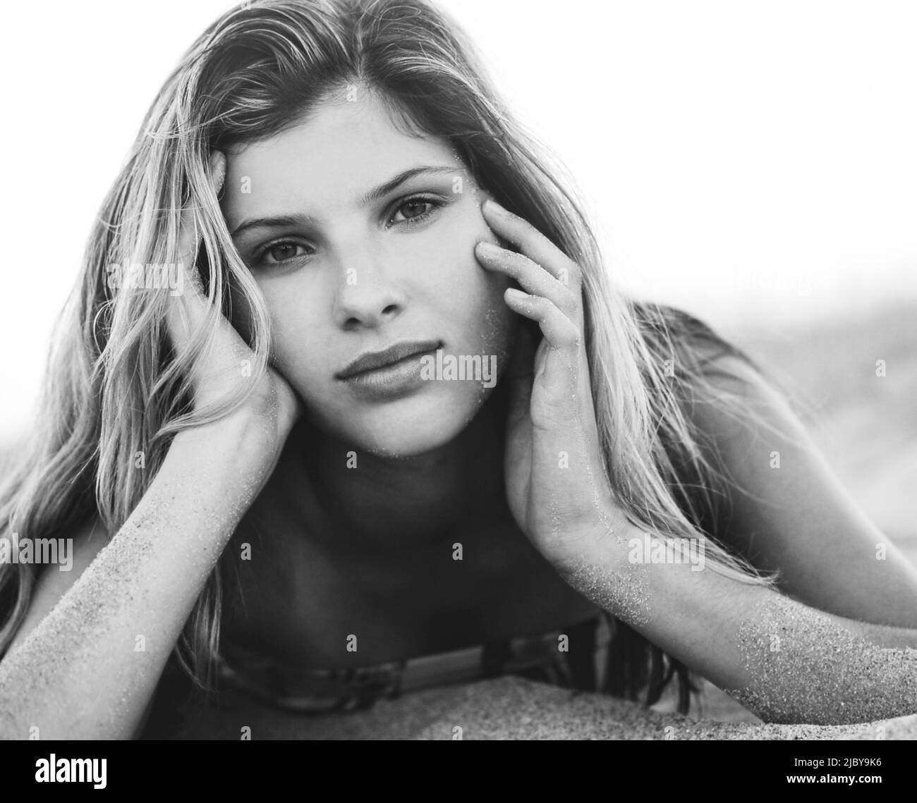 Portrait of young woman resting head on hands laying down in the sand Stock Photo Alamy