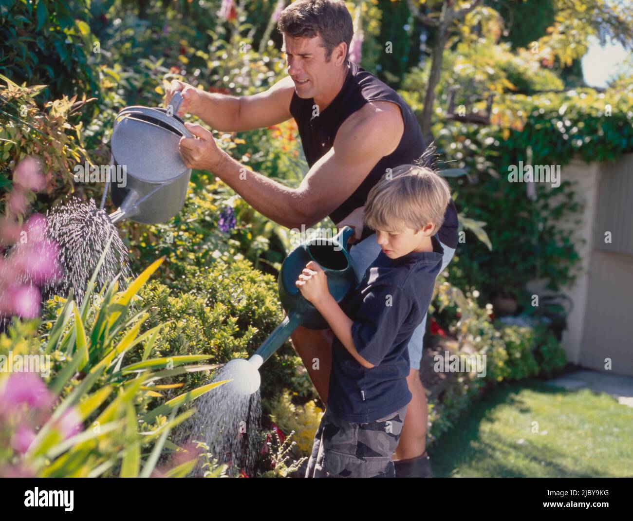 Father and Son watering garden with watering cans Stock Photo - Alamy