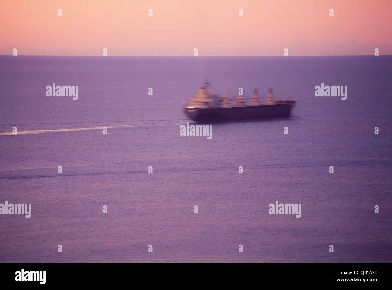 Cargo Ship at sea at dawn Stock Photo - Alamy