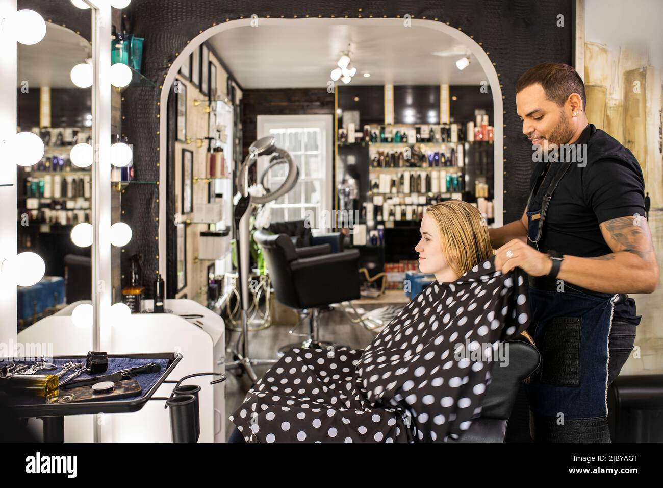 Stylist sitting young woman in chair after washing hair preparing for haircut at boutique salon Stock Photo