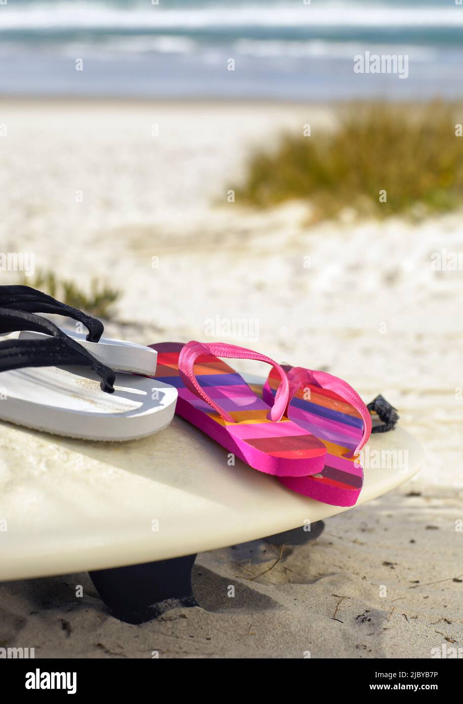 Flip flops resting on surfboard in the sand Stock Photo - Alamy