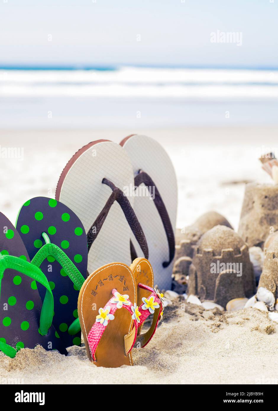 Flip flops standing upright in the sand next to sandcastles Stock Photo ...