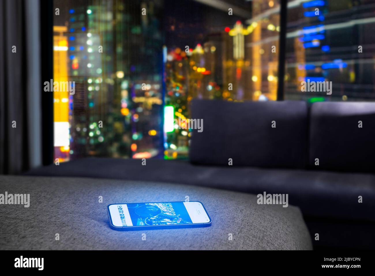 A mobile on a bed in a hotel room at night Stock Photo