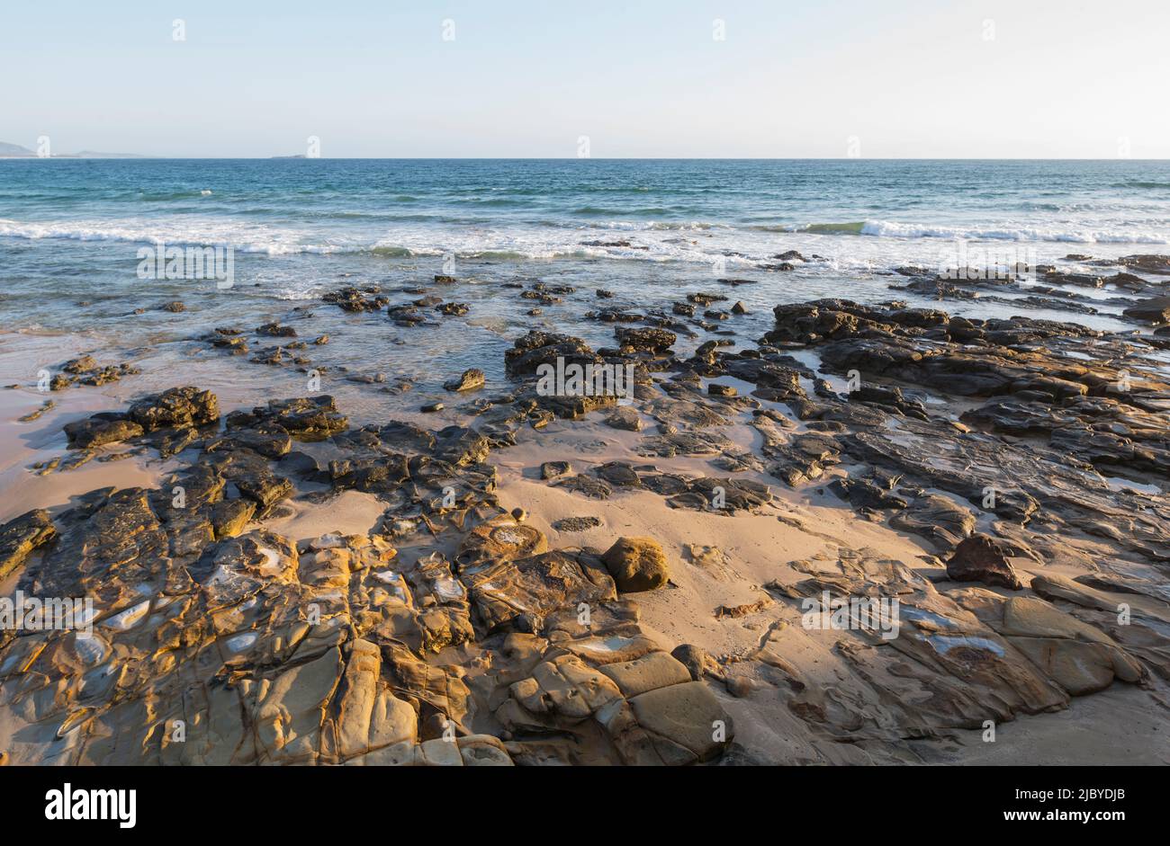 Rocks on beach and waves rolling in at Alexandra Headland Stock Photo