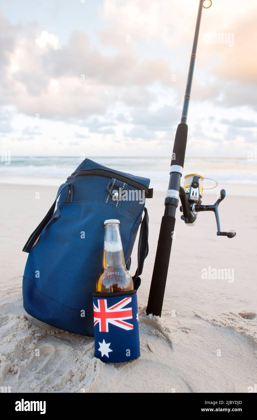 Beer in stubbie holder with Australian Flag, cooler bag and fishing rod on the beach on Australia Day Stock Photo
