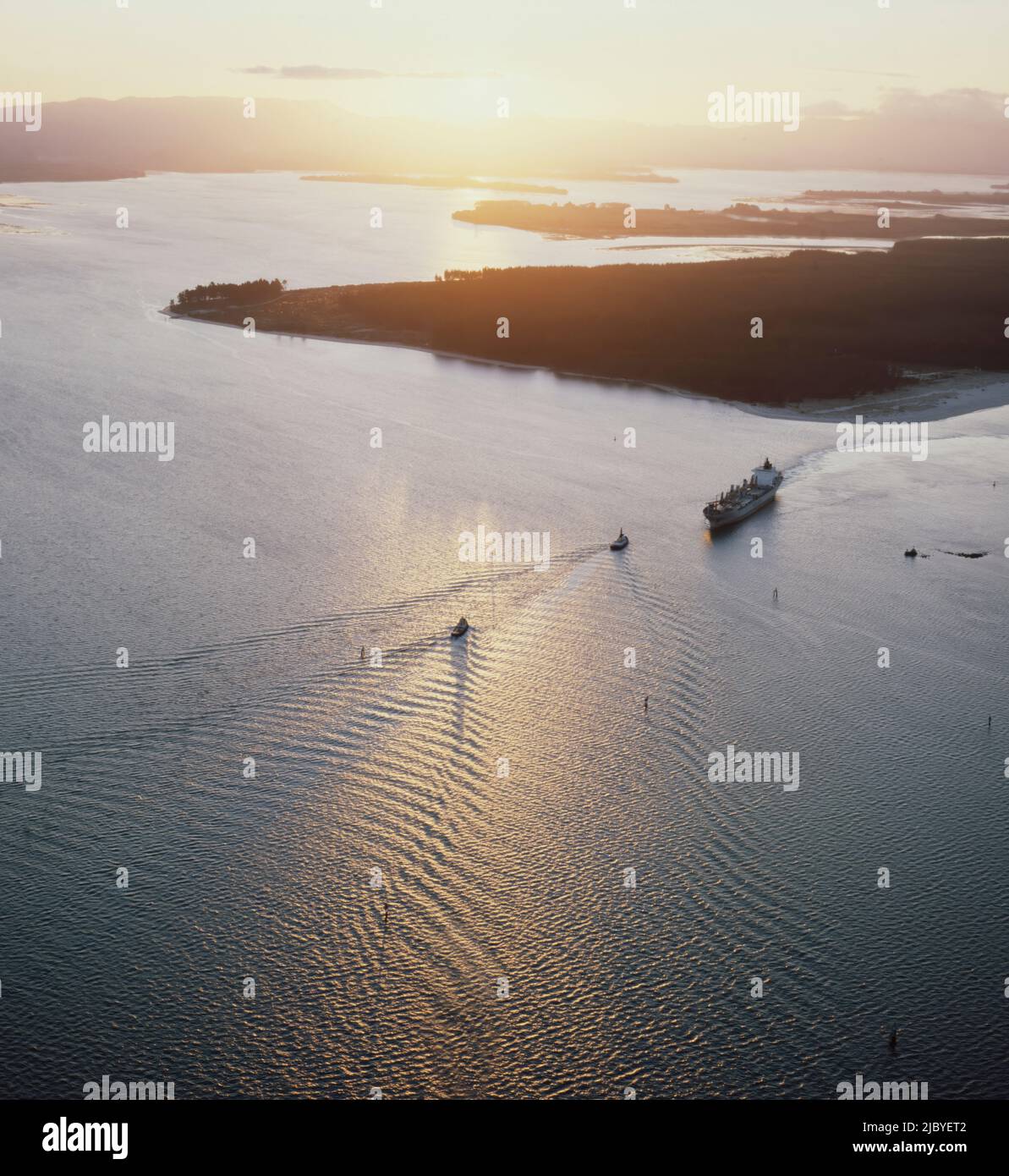 Aerial of cargo ship entering harbour mouth at sunset Stock Photo