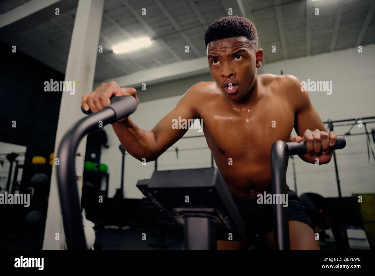 African American male using an elliptical trainer during cross fit training. Male athlete exercising intensely in the gym. High quality photo Stock Photo
