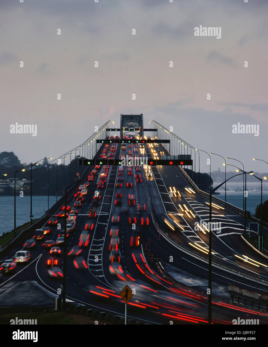 Traffic flowing both ways on Auckland Harbour Bridge at dusk Stock