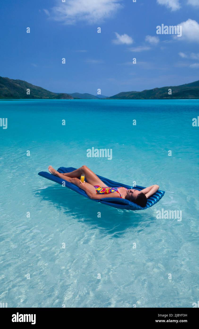 Young Woman floating on a lilo at Whitehaven Beach - Queensland Stock Photo