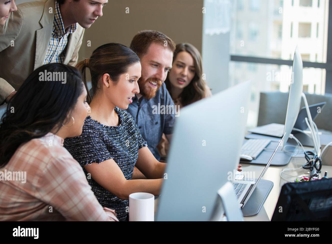Young woman using laptop computer in conference room showing co-workers ...