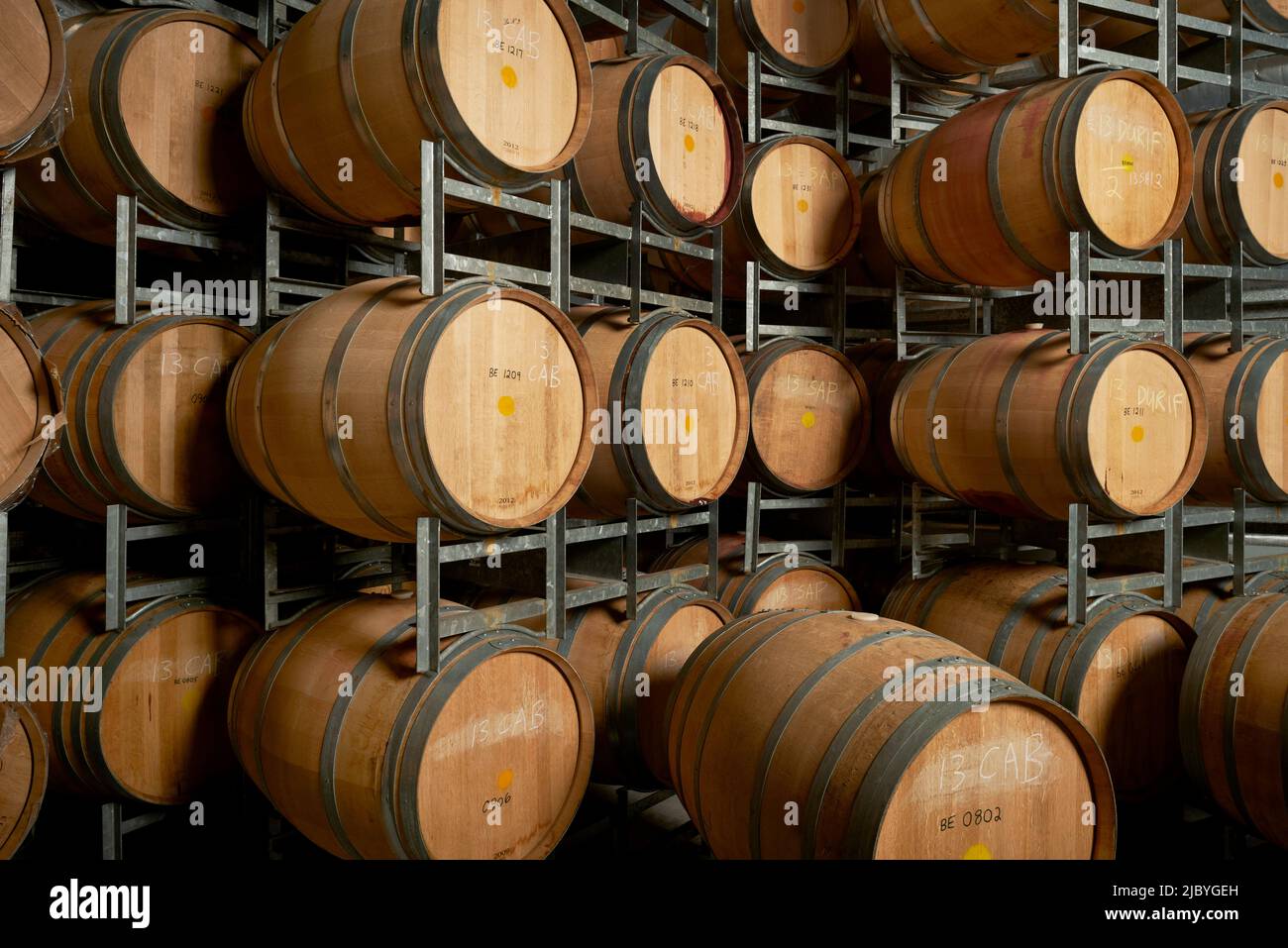 Rows of wine barrels on storage racks in cellar for aging wine Stock Photo