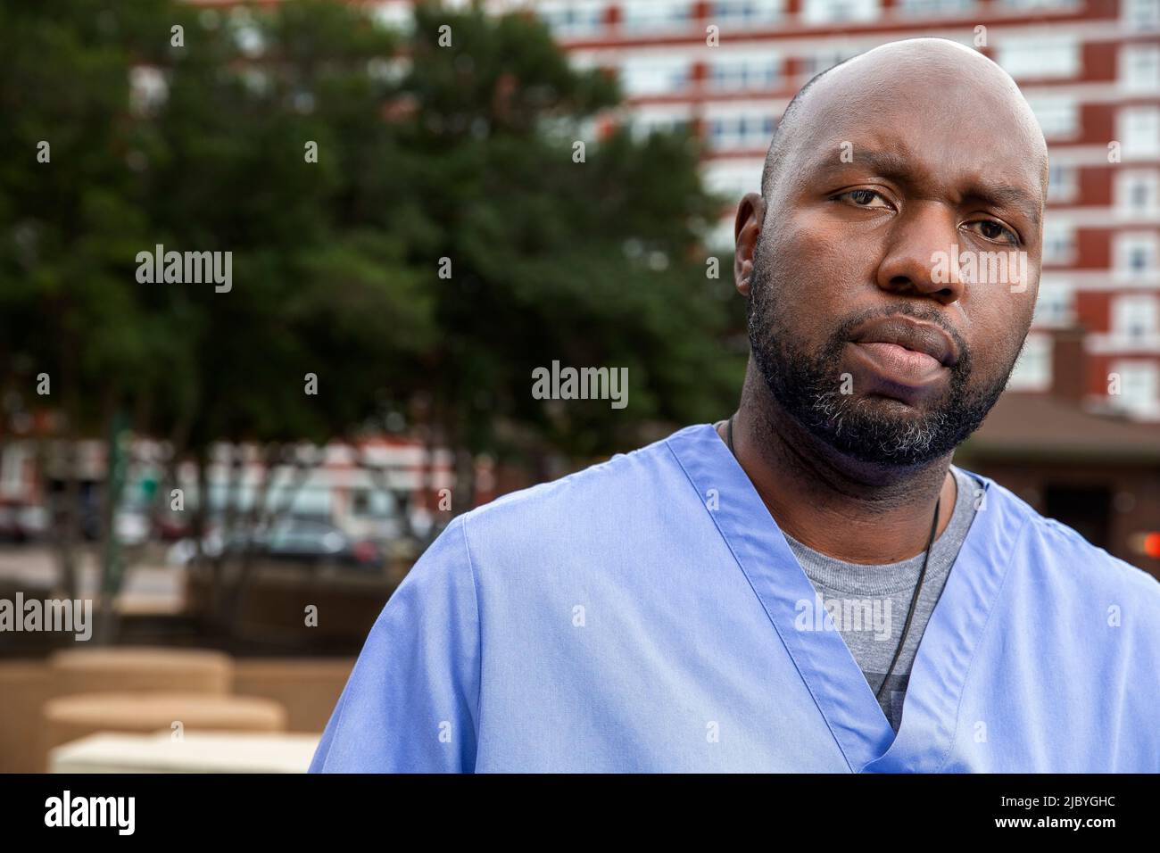 Portrait of middle aged man with beard and a bald head wearing scrubs standing outside looking at camera Stock Photo