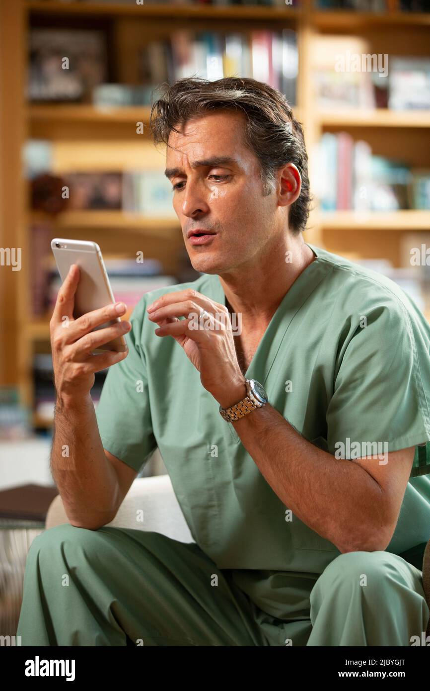 Hispanic Male doctor practicing tele-medicine from his home office, Talking to patient on video call Stock Photo