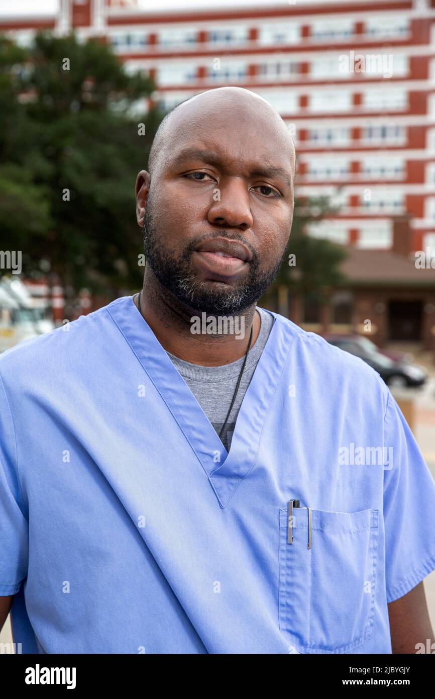 Portrait of middle aged man with beard and a bald head wearing scrubs standing outside looking at camera Stock Photo
