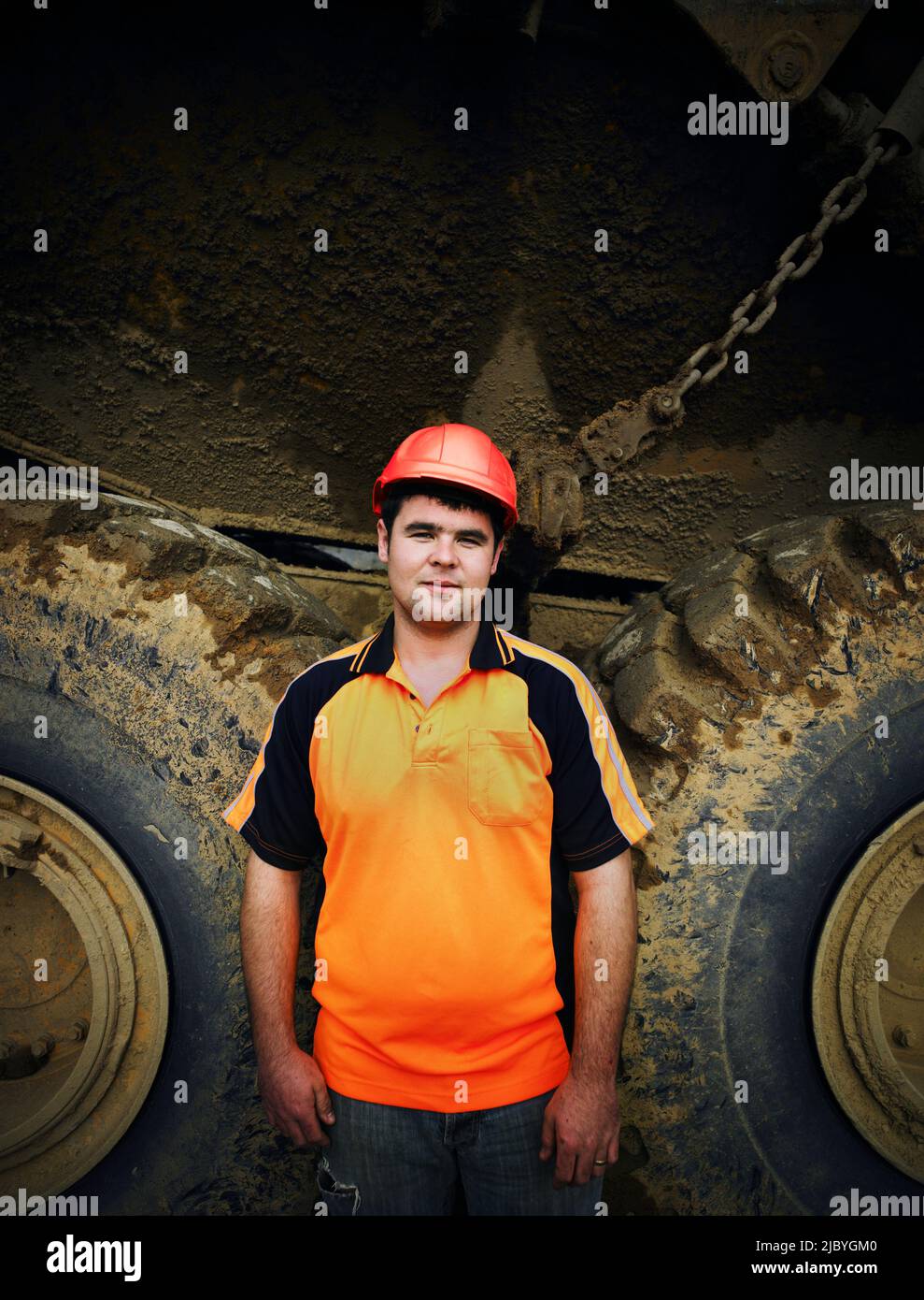 Portrait of driver next to the large wheels of an earth moving truck