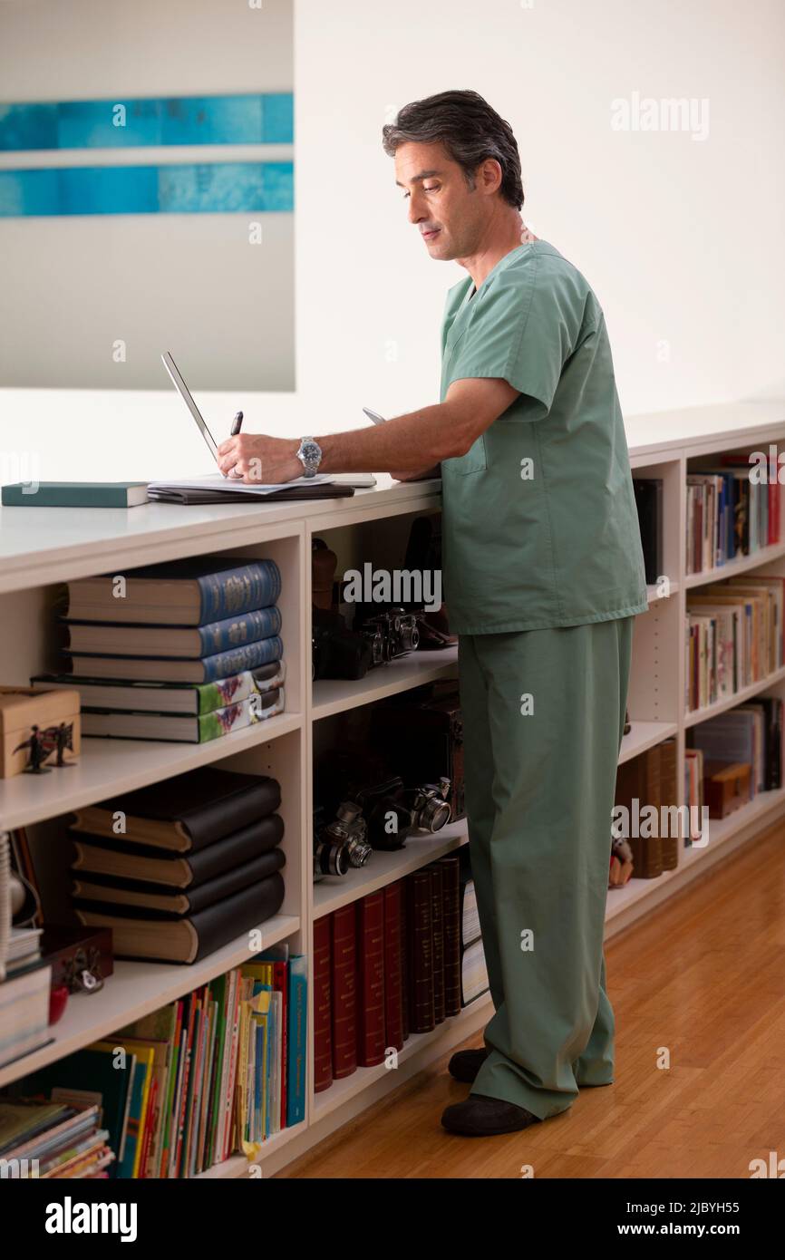 Hispanic Male doctor in his home practicing Telemedicine taking notes Stock Photo