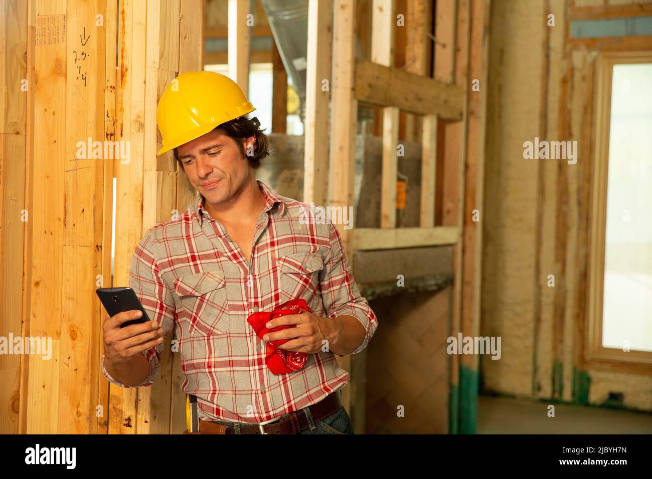 Construction worker wearing hard-hat on job site using mobile phone Stock Photo