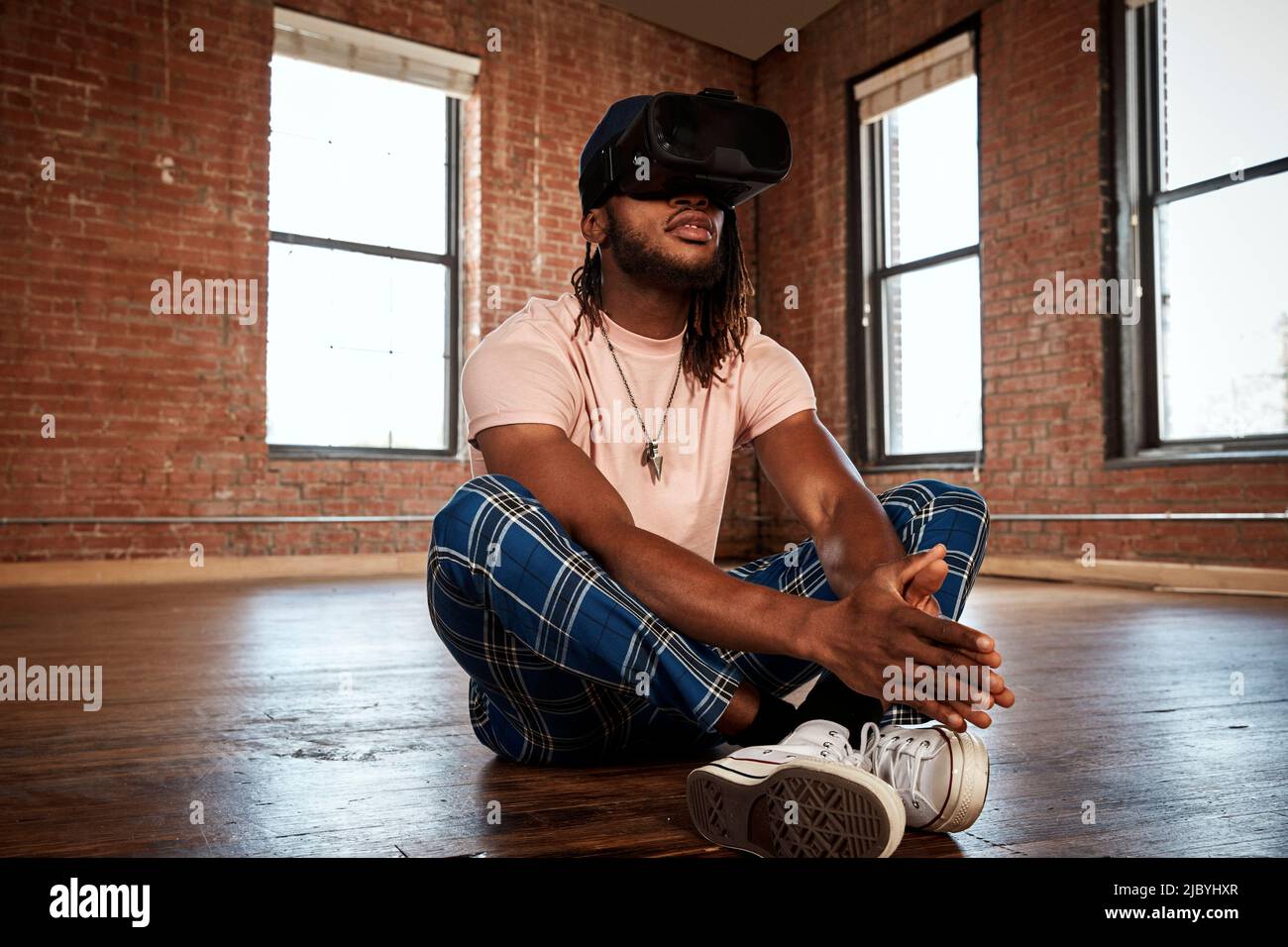 portrait of stylish young ethnic man wearing VR headset in empty loft space Stock Photo