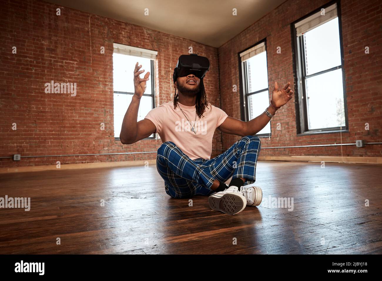 portrait of stylish young ethnic man wearing VR headset in empty loft space Stock Photo